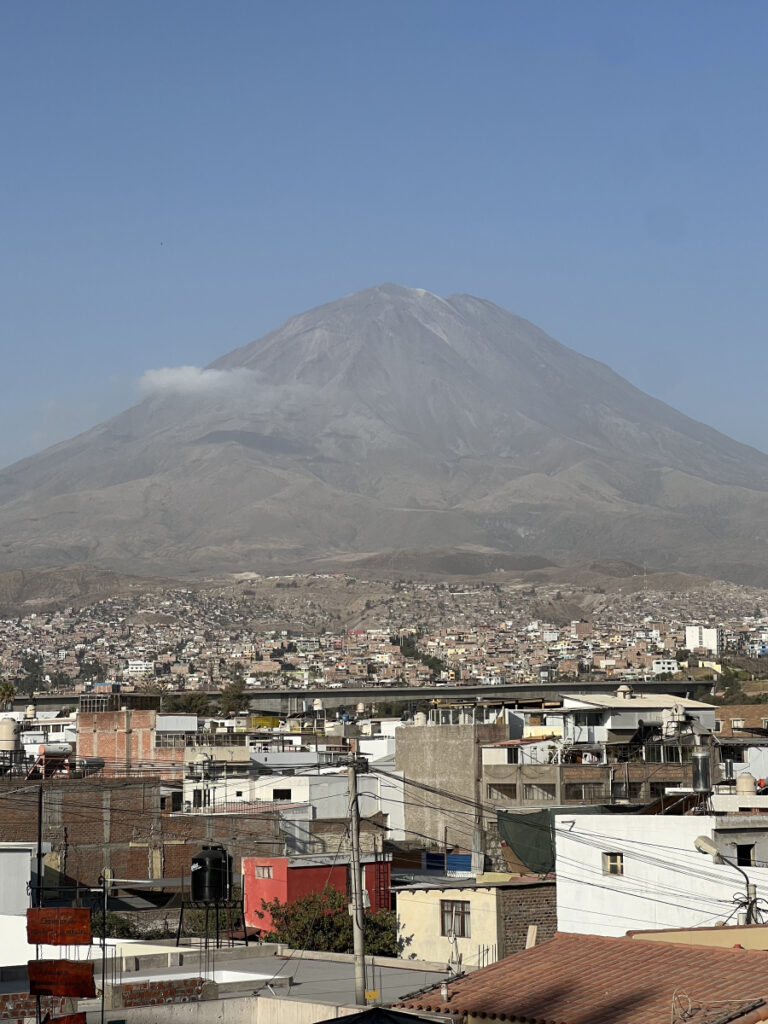 View of El Misti volcano rising above the rooftops of Arequipa, Peru, under a clear blue sky.