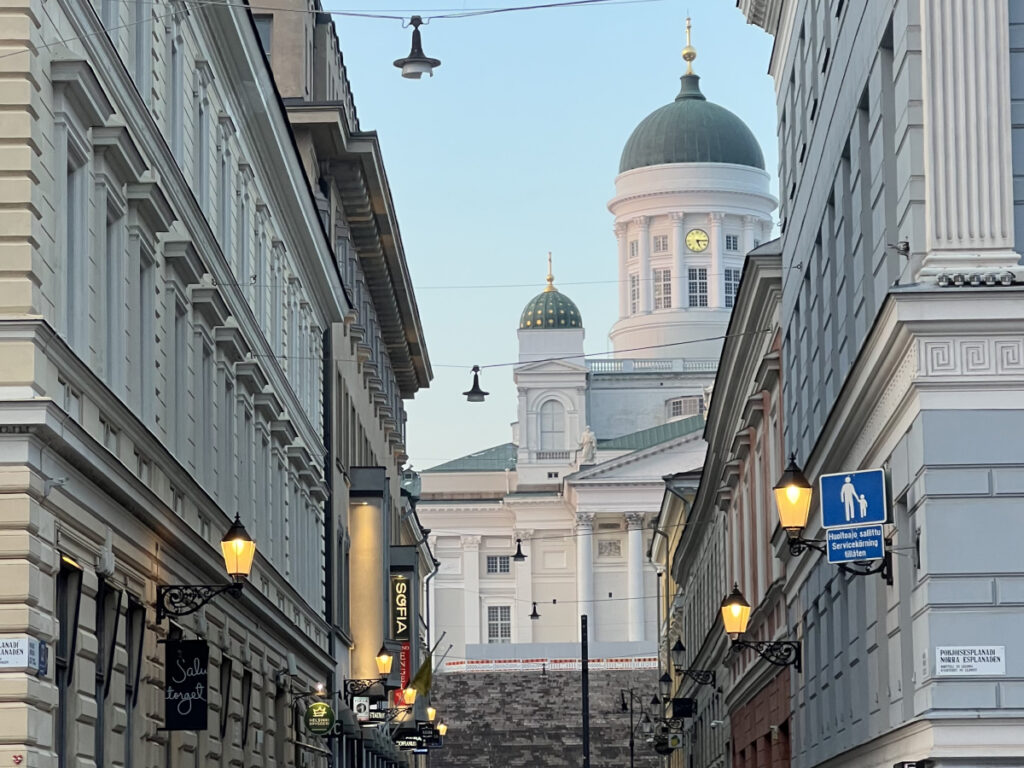 View of Helsinki Cathedral from a side street at sunset, with warm street lights and neoclassical architecture in Finland.