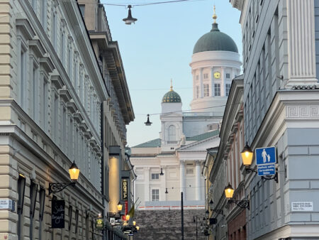 View of Helsinki Cathedral from a side street at sunset, with warm street lights and neoclassical architecture in Finland.