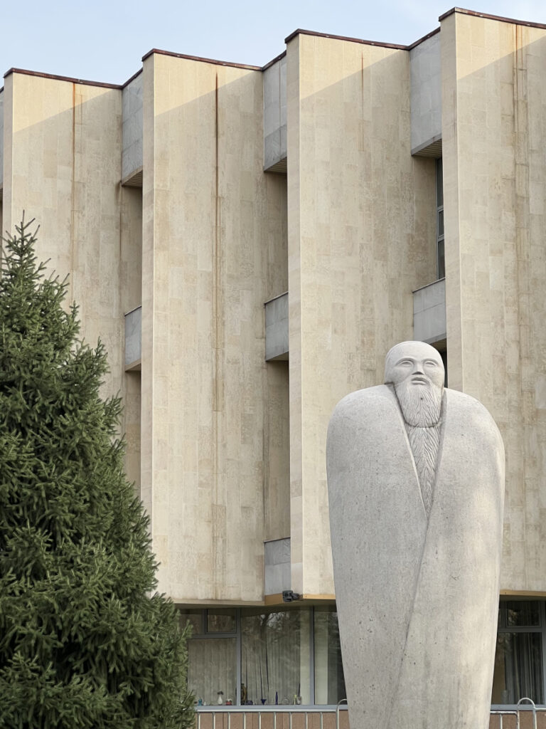 Stone sculpture outside the Kasteyev State Museum of Arts in Almaty, Kazakhstan, set against the museum’s modernist concrete façade