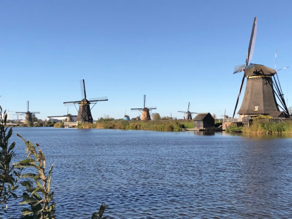 Historic windmills at Kinderdijk along the canal on a clear blue sky day — a top day trip from Amsterdam in the Netherlands