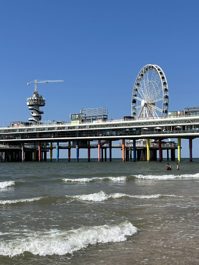 Colorful pier and Ferris wheel at Scheveningen Beach near The Hague, with waves rolling in from the North Sea