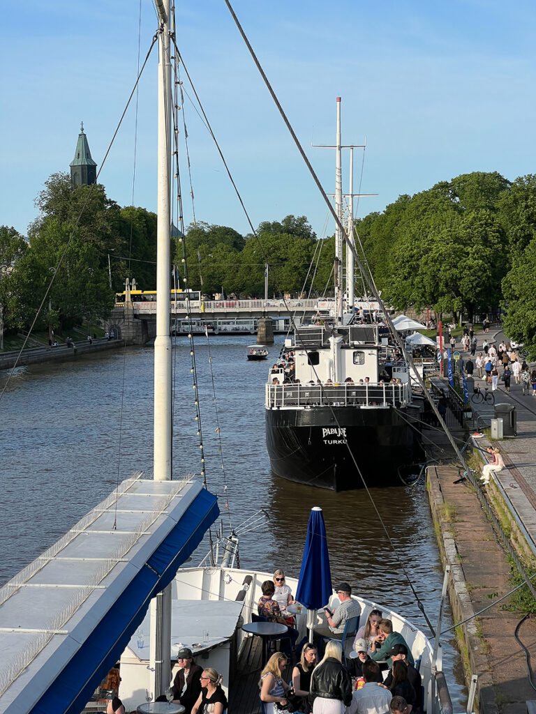 Turku riverfront with boats and people enjoying a sunny summer day.