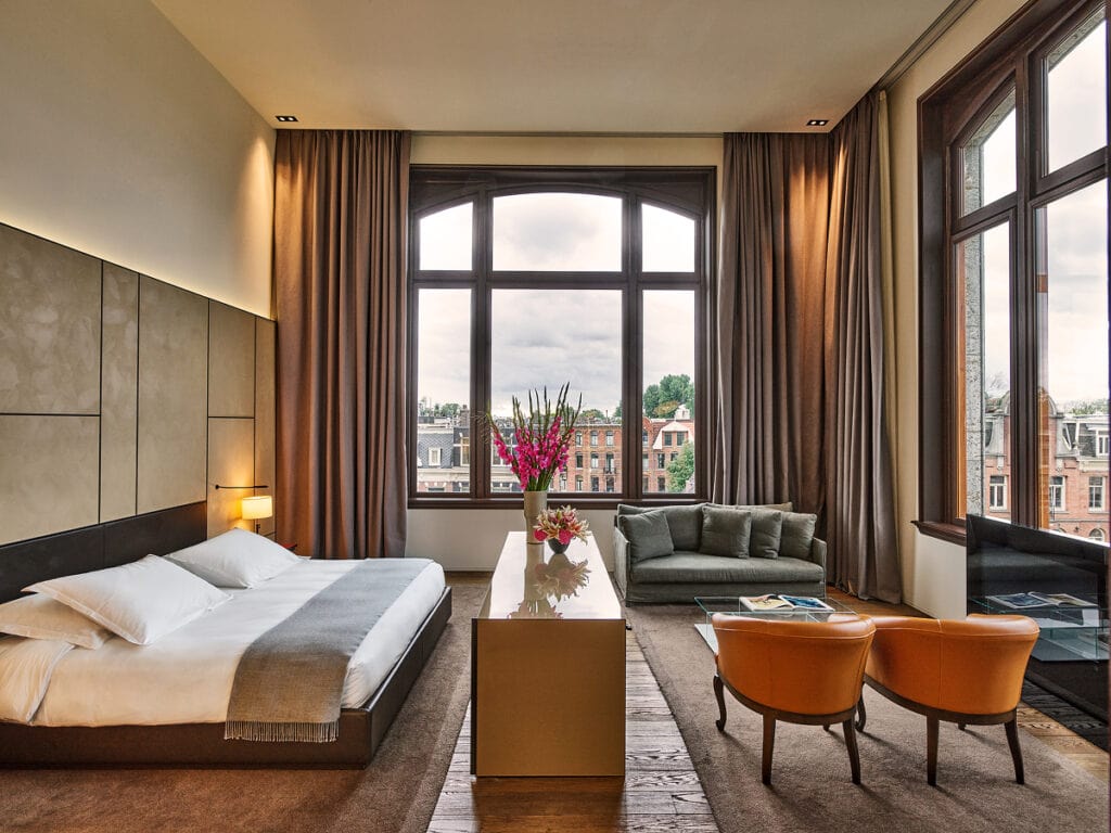 Interior of the Conservatorium Hotel, one of the best hotels in Amsterdam, featuring a spacious room with large windows and a city view.