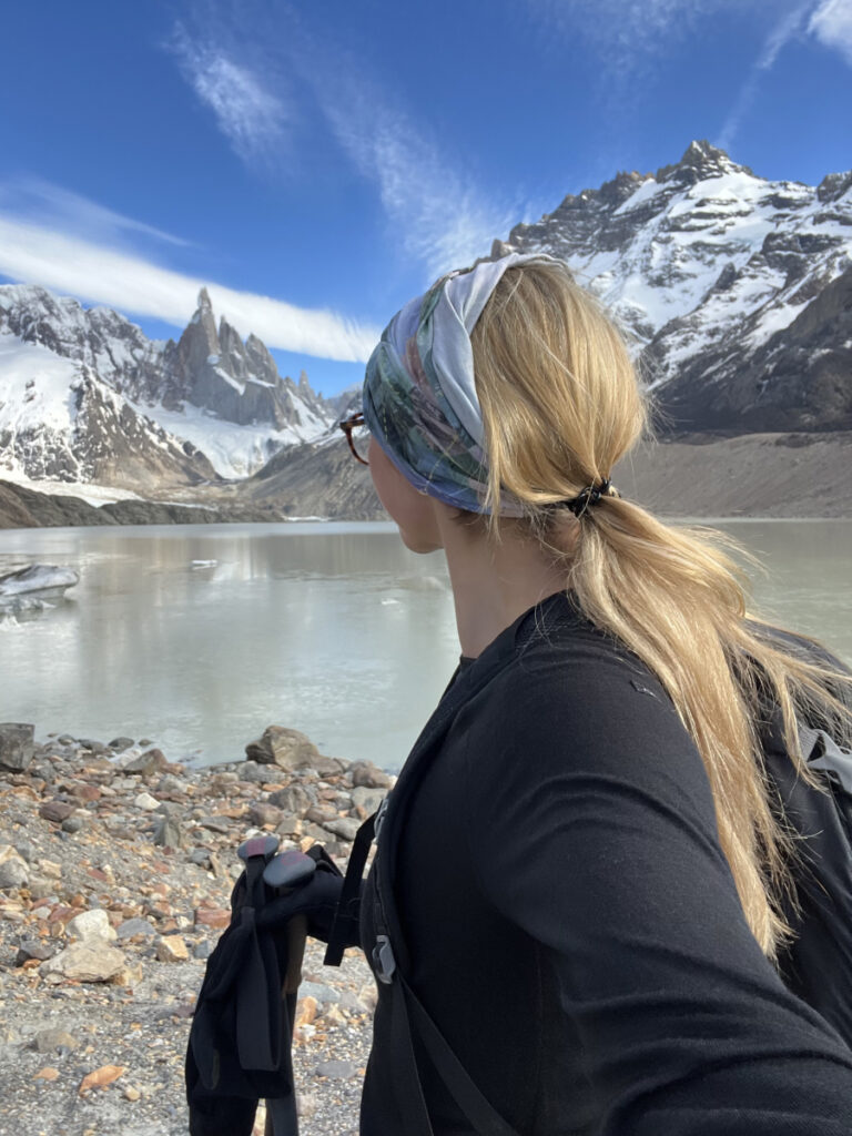 Woman hiking near Laguna de los Tres with Mount Fitz Roy in the background on a clear day in Patagonia