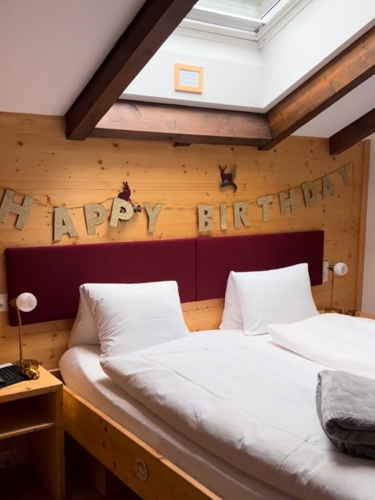 Hotel Capricorn Zermatt room decorated with Happy Birthday banner, wooden chalet walls, and cozy alpine bedding.