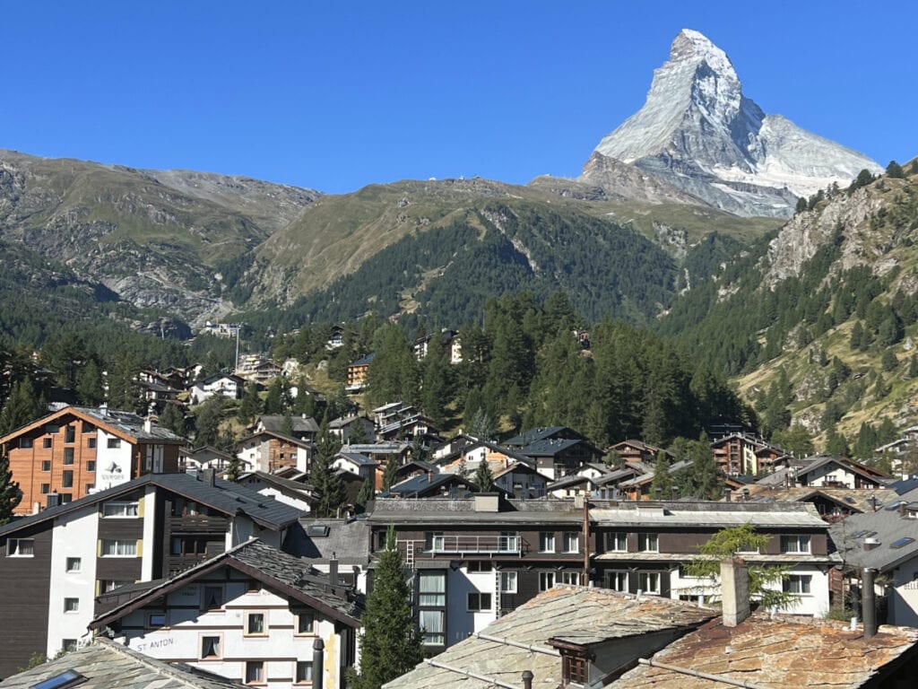 View of the Matterhorn from Hotel Capricorn Zermatt balcony overlooking the alpine village rooftops.