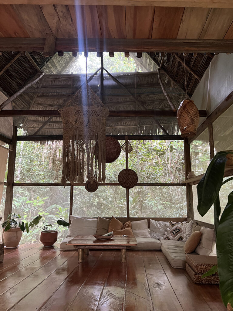 Open-air lounge in a jungle Airbnb in Nauta, Peruvian Amazon, with rustic wood floors, plants, and jungle views
