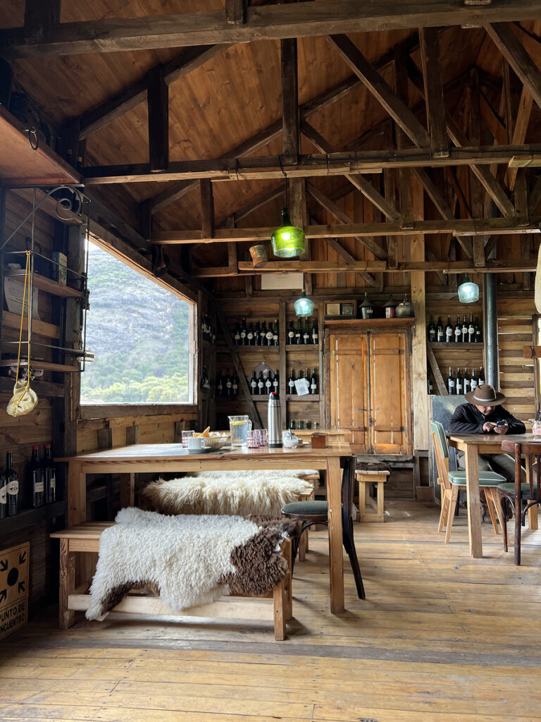 Interior of La Pulpería restaurant at Estancia Bonanza in El Chaltén, with rustic wooden decor and sheepskin-covered benches