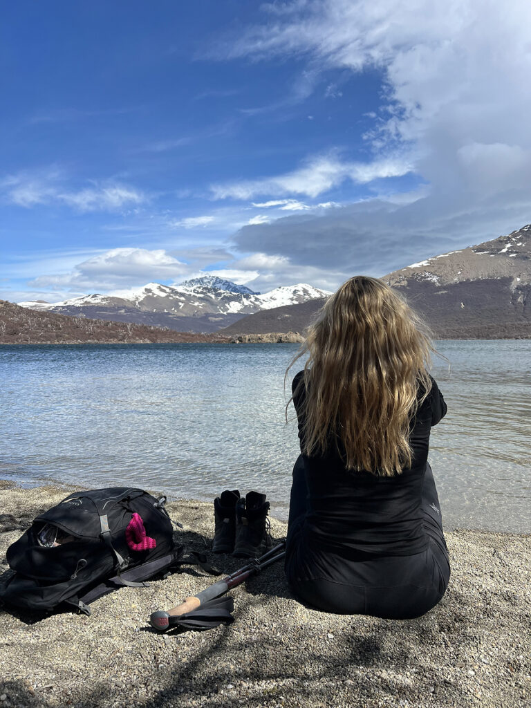 Woman resting at the edge of Laguna Capri near El Chaltén after hiking from Laguna de los Tres