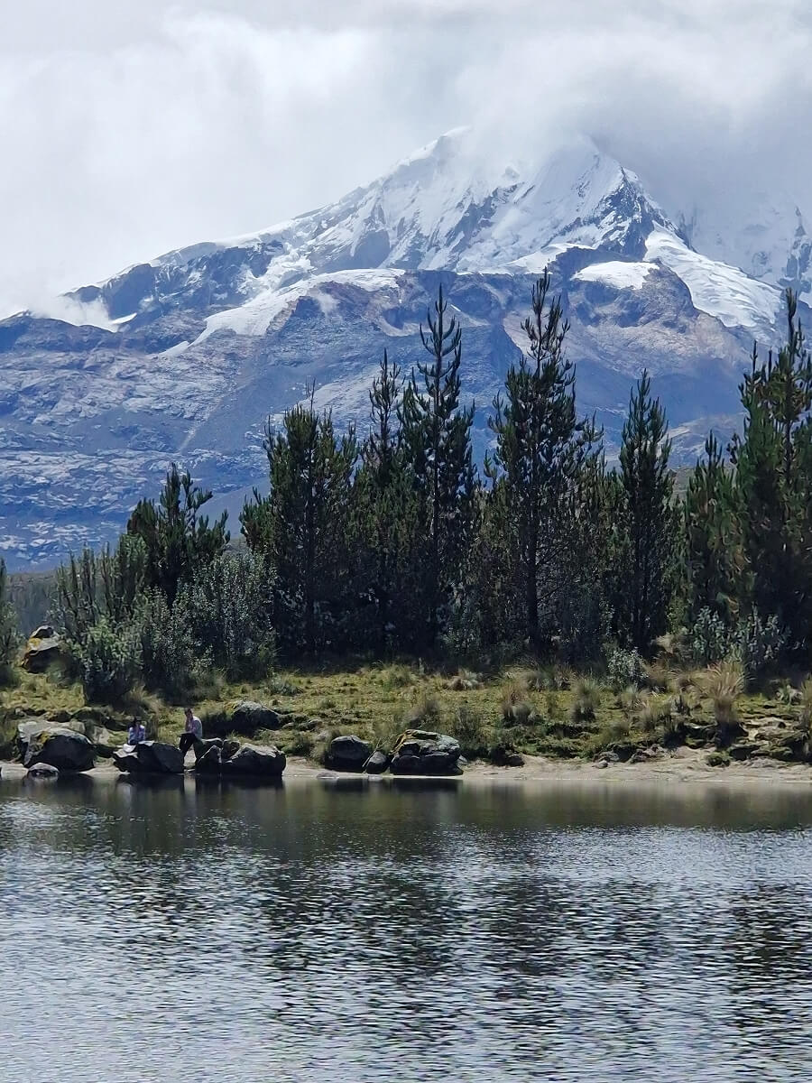 Laguna Radian hike near Huaraz, Peru, with reflective lake and distant mountains under blue skies.
