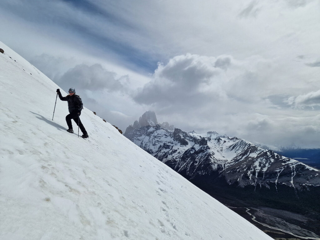 Hiker ascending a steep snowy slope on the Loma del Pliegue Tumbado trail near El Chaltén, Argentina