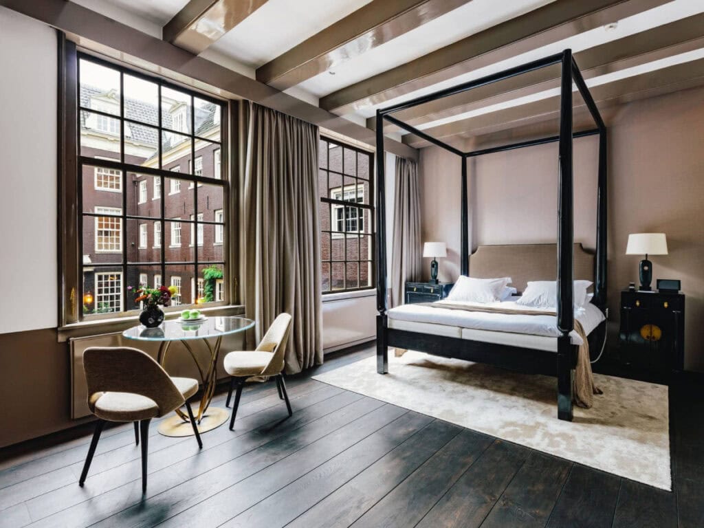 Elegant luxury room at The Dylan Amsterdam with four-poster bed and canal-side views — one of the best boutique hotels in Amsterdam.